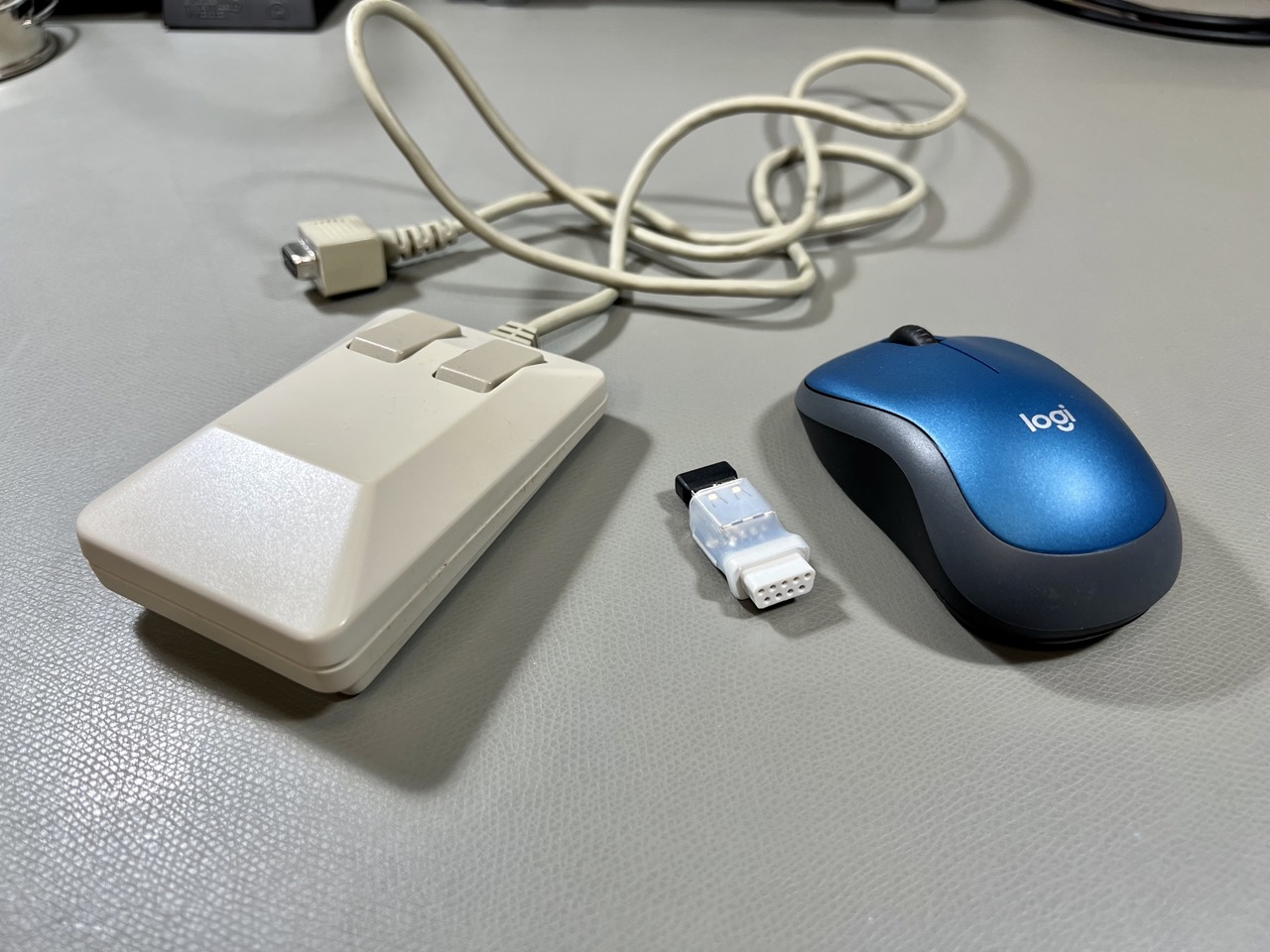 A vintage Commodore 1351 mouse, and a mouSTer USB mouse converter with a modern wireless Logitech M185.